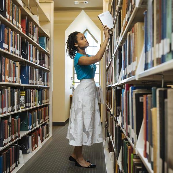 一个女学生从图书馆书架上取下一本书